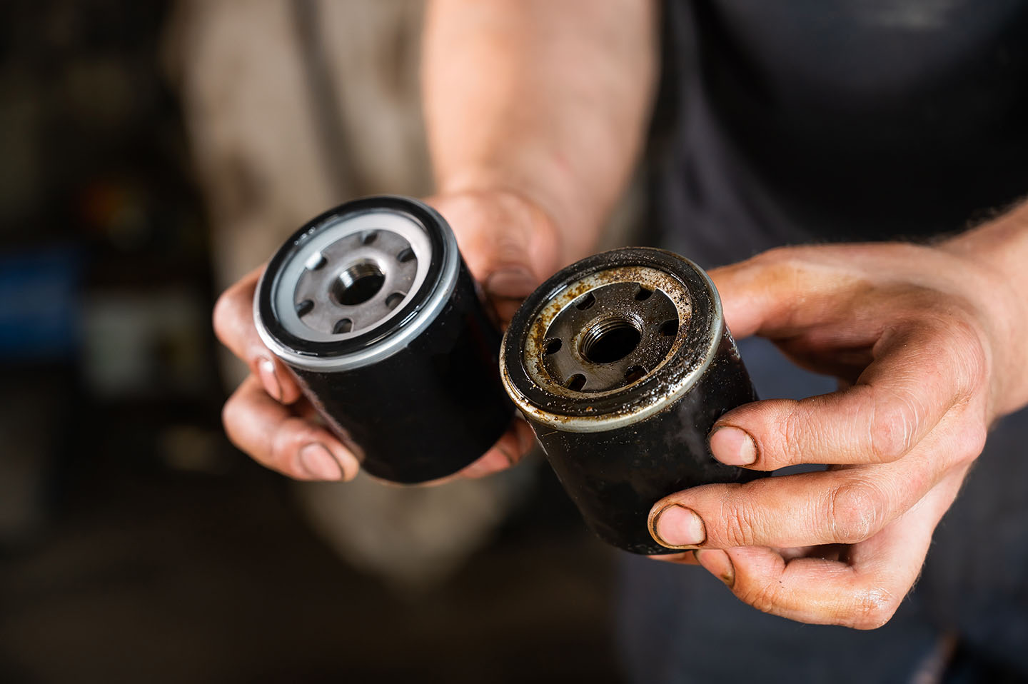 auto mechanic holds new and used oil filter