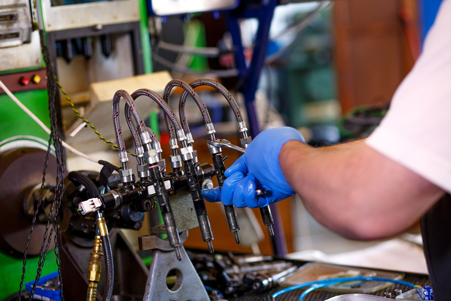 Professional mechanic testing diesel injector in his workshop.